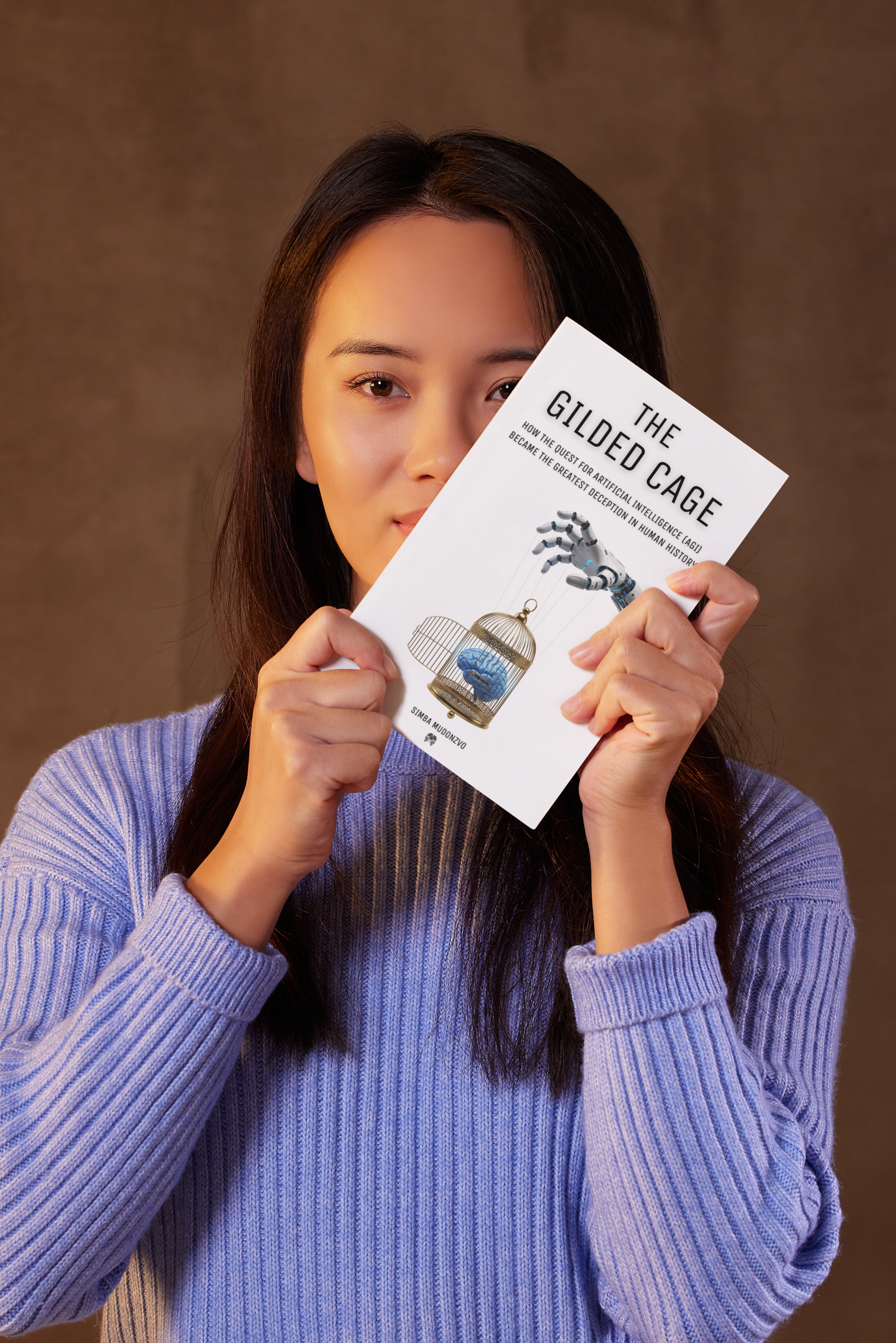 A chinese AI researcher who works at OpenAI holding the book The Gilded Cage - How the Quest for Artificial Intelligent (AGI) Became the Greatest Deception in Human History.